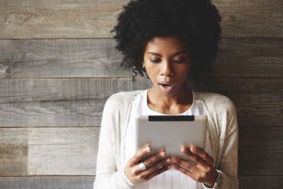 Shocked Woman Looking at the Writing on a Landing Page on Tablet